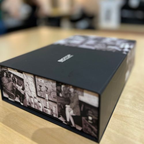 Coffret cadeau Biotop 700 fermé, boîte noire avec visuel rétro noir et blanc sur les côtés, posé sur une table en bois clair. Packaging professionnel et élégant contenant une routine capillaire complète pour cheveux abîmés ou traités chimiquement.