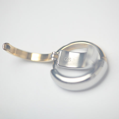 Boucle d’oreille créole ouverte en métal bicolore, avec intérieur doré et extérieur argenté, posée sur fond blanc. Gravure “C&S” visible à l’intérieur du fermoir. Finition brillante et moderne.