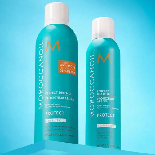 Flacons du Protecteur Absolu Moroccanoil posés côte à côte sur fond bleu. Spray thermo-protecteur cheveux en édition limitée 300 ml et format classique, contenants turquoise avec bouchon blanc, lettrage vertical blanc et logo orange. Soin protecteur contre la chaleur jusqu’à 230 °C, enrichi en huile d’argan.