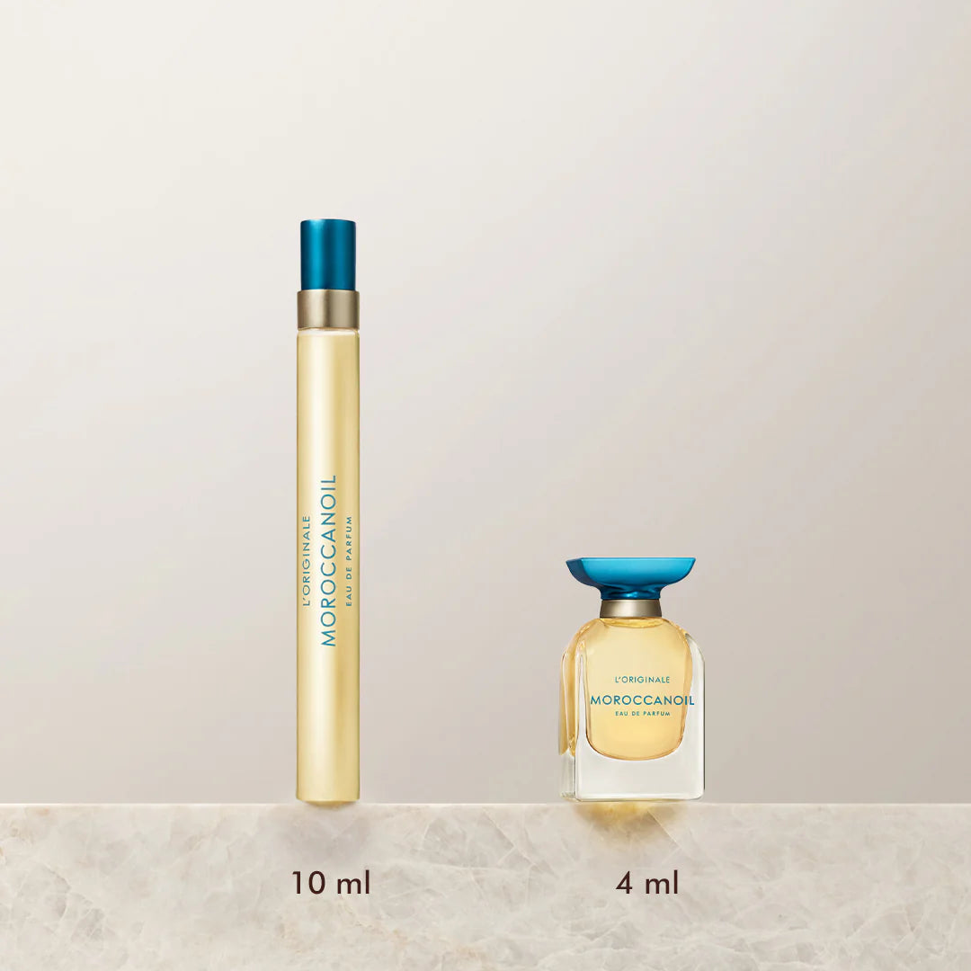 Deux formats du parfum Moroccanoil L'Originale posés sur une surface en marbre beige : flacon vaporisateur 10 ml en tube doré avec bouchon turquoise et flacon miniature 4 ml en verre transparent avec bouchon plat bleu. Parfum iconique à l’huile d’argan, ambiance élégante et minimaliste sur fond beige clair.