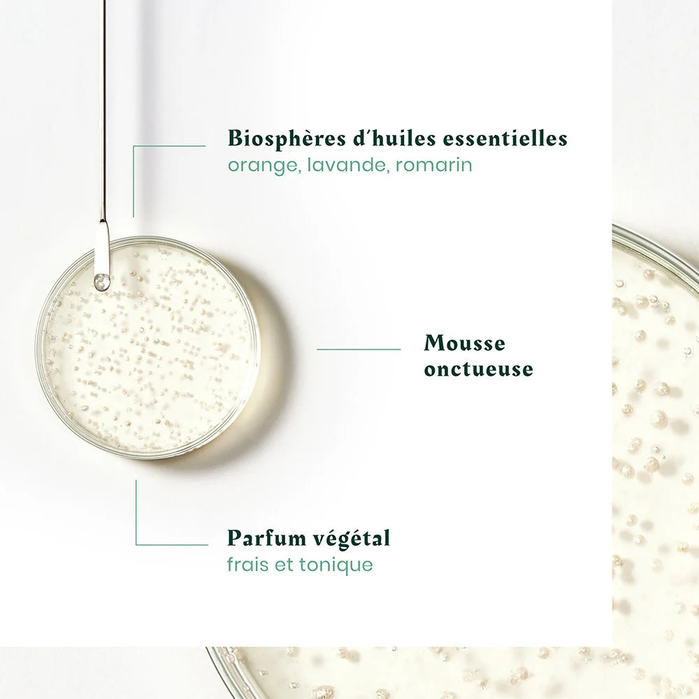 Zoom sur texture du shampoing Triphasic avec micro-billes et mention biosphères d’huiles essentielles orange lavande romarin, fond clair esthétique
