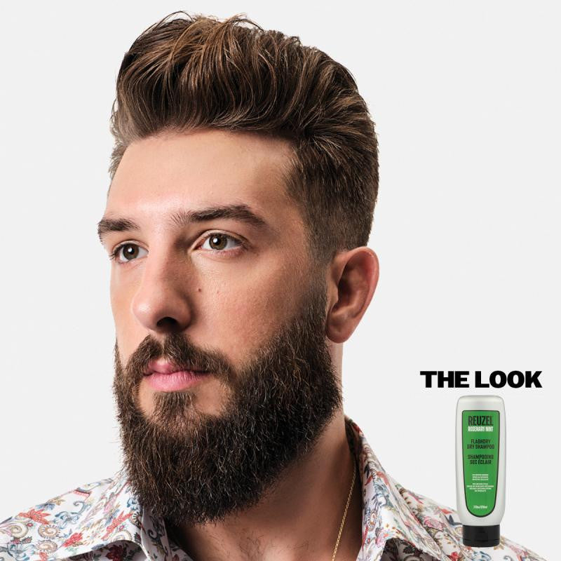 Homme à barbe fournie avec une coupe coiffée vers l’arrière, accompagné du shampoing sec Reuzel Flashdry en bas à droite avec la mention "The Look".