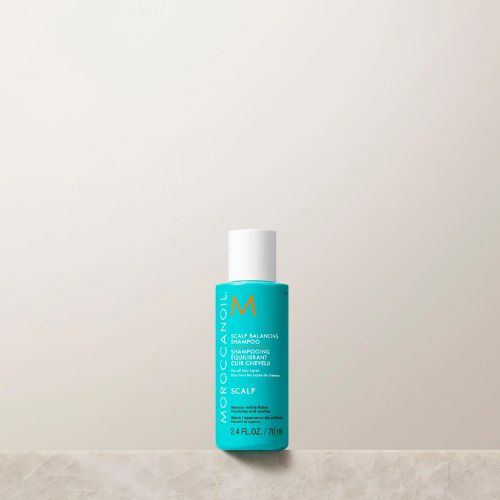 Shampoing Moroccanoil Équilibrant pour le cuir chevelu, format 70 ml. Bouteille turquoise au design minimaliste avec bouchon blanc, logo orange et texte blanc. Soin doux pour cuir chevelu sensible ou déséquilibré, présenté sur une surface en marbre beige avec fond neutre.