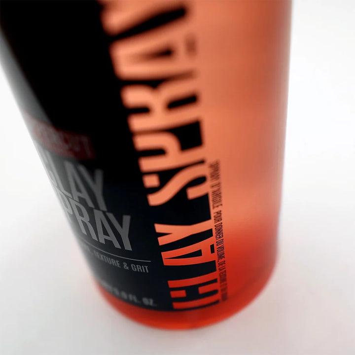 Zoom sur flacon Uppercut Clay Spray rouge translucide avec lettrage noir “Clay Spray”, détail du design moderne sur fond blanc