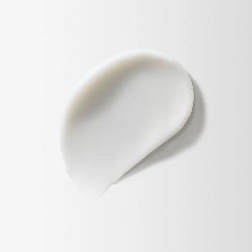 Texture crémeuse blanche du soin capillaire Moroccanoil, vue en gros plan sur fond blanc. Fini onctueux et hydratant, illustrant la richesse et la douceur du produit pour les cheveux ou le cuir chevelu.