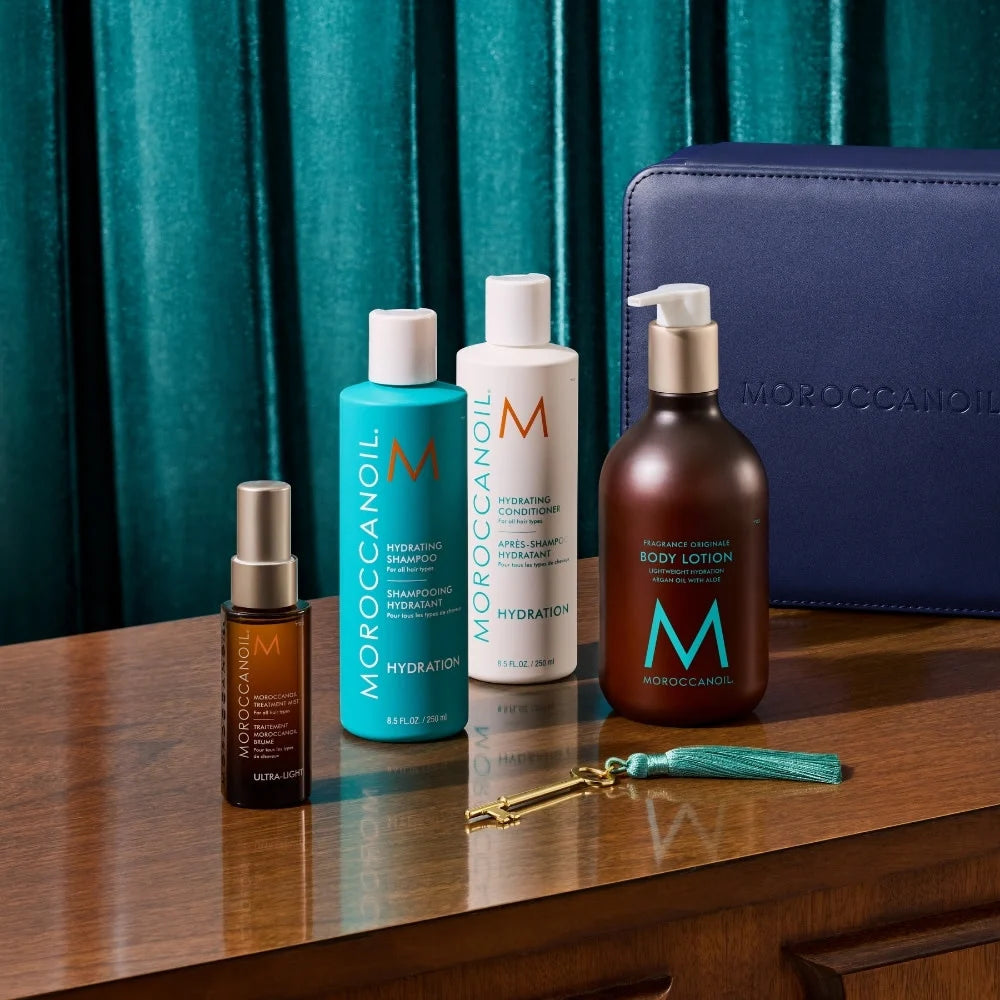 Produits de l’Ensemble Hydratant Moroccanoil sur table en bois avec shampooing, après-shampooing, brume ultra-légère, lotion corps et coffret bleu.