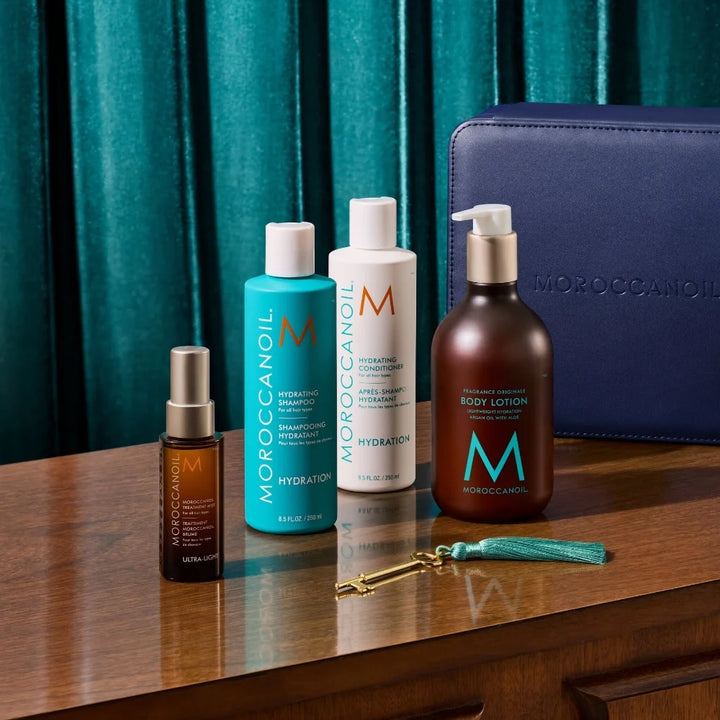 Produits de l’Ensemble Hydratant Moroccanoil sur table en bois avec shampooing, après-shampooing, brume ultra-légère, lotion corps et coffret bleu.