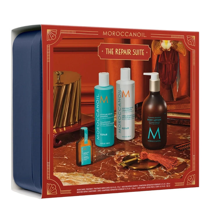 Produits de l’Ensemble Réparateur MOROCCANOIL avec shampooing, après-shampooing, huile capillaire, lotion corps et coffret bleu marine sur table en bois.