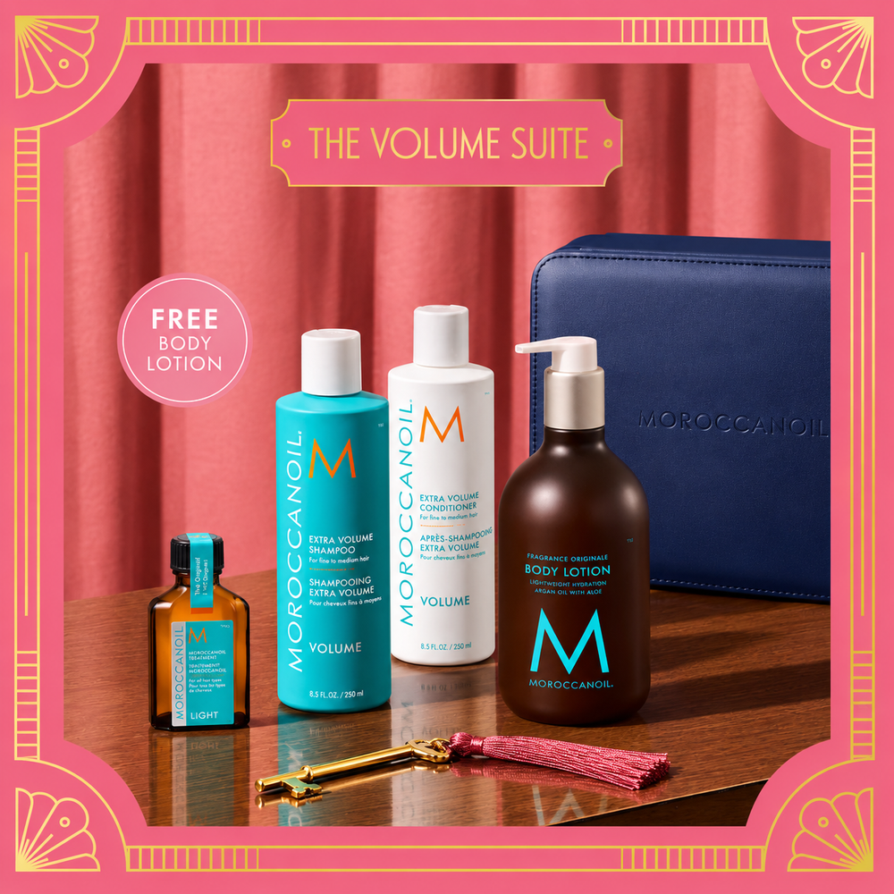 Ensemble Volume Moroccanoil avec shampooing et après-shampooing Extra Volume, Traitement Léger, lotion corps et coffret bleu marine sur décor rose.