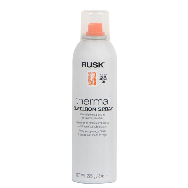 Aérosol de 226 g du spray thermo-protecteur RUSK Thermal Flat Iron Spray, avec bouchon orange et étiquette blanche. Mention “à l’huile d’argan pure” sur le flacon, conçu pour protéger les cheveux lors du coiffage à chaud.