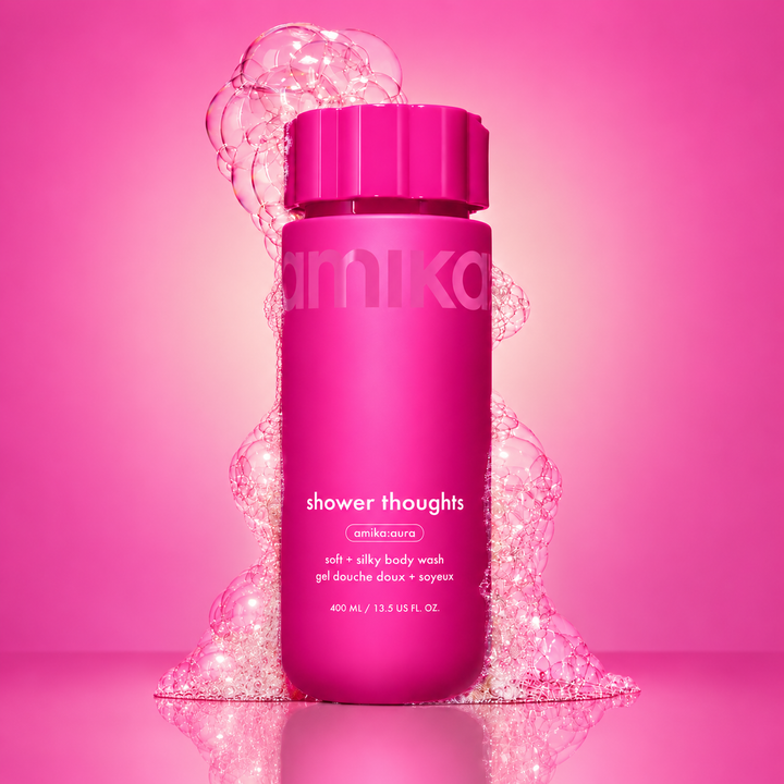 AMIKA Shower Thoughts gel douche doux et soyeux 400 ml, bouteille rose fuchsia avec bulles transparentes sur fond rose.