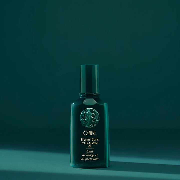 Huile capillaire Oribe Eternal Curls Polish & Protect Oil présentée sur fond vert foncé pour nourrir, protéger et faire briller les cheveux bouclés.