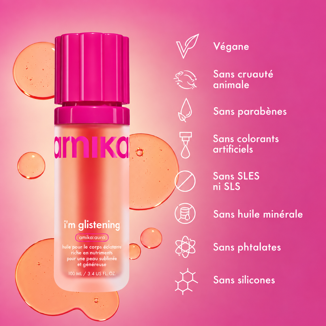 huile corporelle éclatante en flacon rose entouré de gouttes d'huile sur fond rose, format de 100 ml.