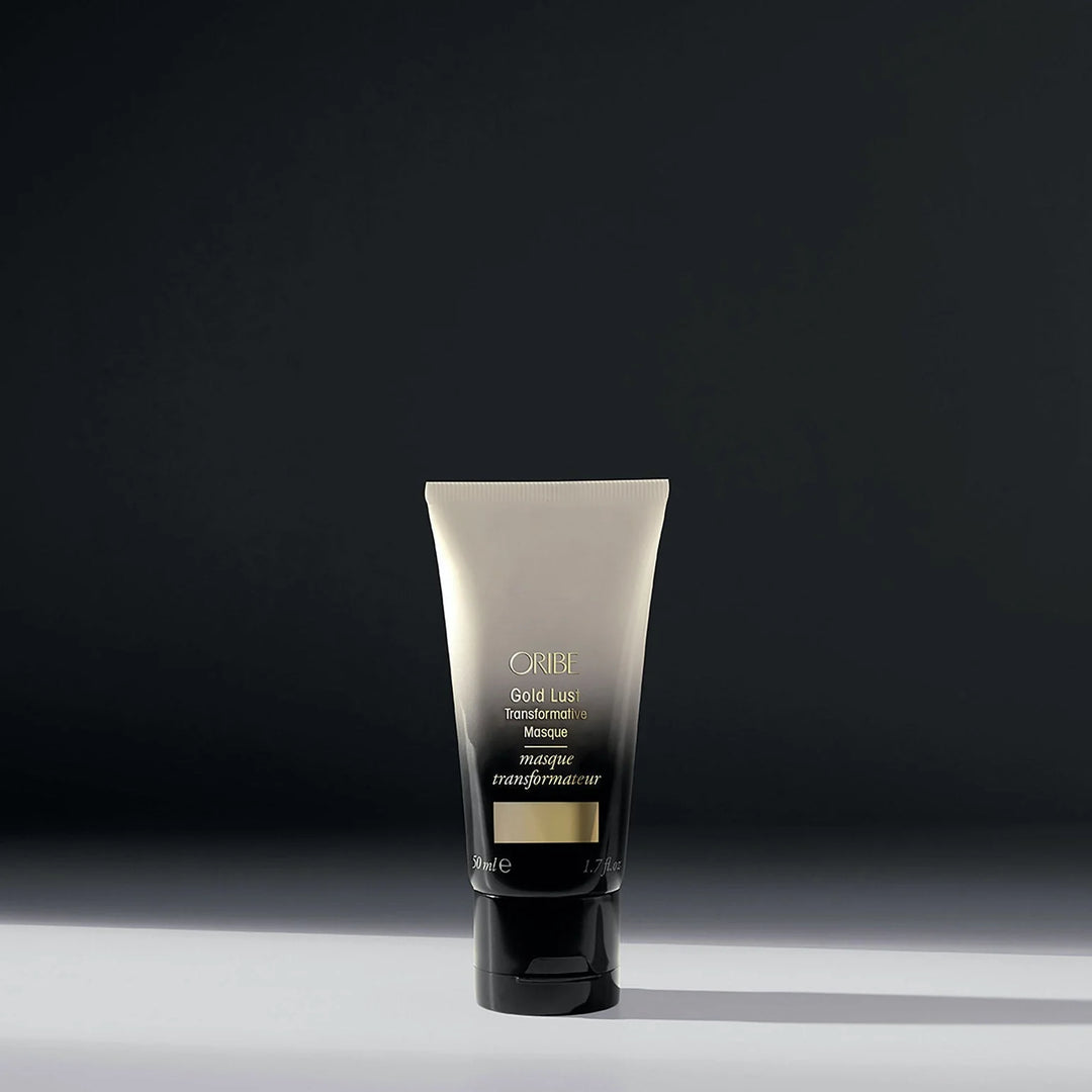 Masque transformateur réparateur ORIBE Gold Lust 50 ml format voyage, tube dégradé ivoire et noir avec inscription dorée et bouchon noir, sur fond sombre.