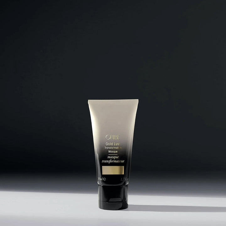 Masque transformateur réparateur ORIBE Gold Lust 50 ml format voyage, tube dégradé ivoire et noir avec inscription dorée et bouchon noir, sur fond sombre.
