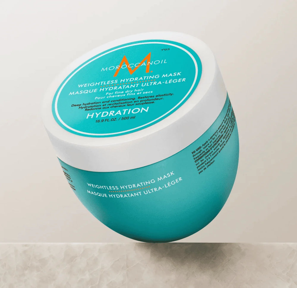 Masque hydratant ultra-léger Moroccanoil 500 ml pour cheveux fins et secs, pot turquoise avec couvercle blanc et logo orange, présenté en angle sur fond beige.