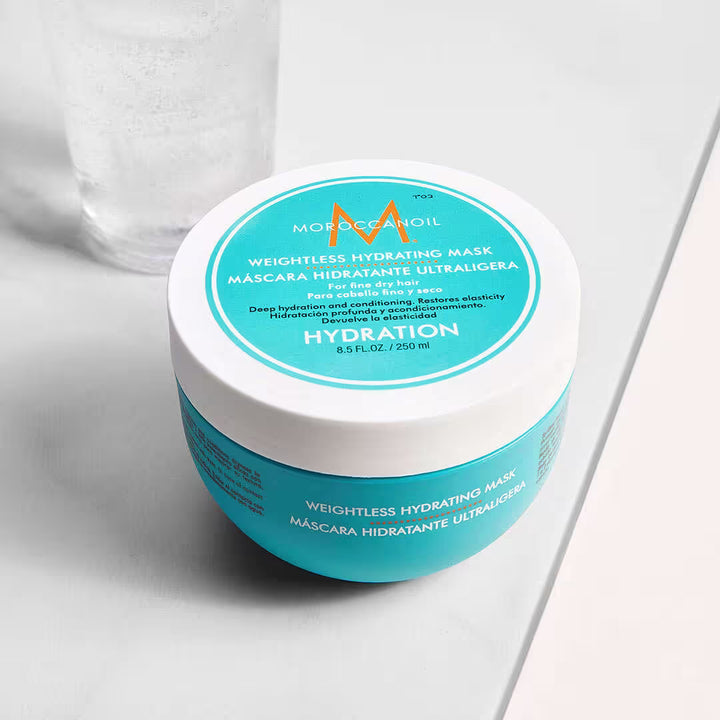 Masque hydratant ultra-léger Moroccanoil 250 ml pour cheveux fins et secs, pot turquoise avec couvercle blanc et logo orange, présenté en angle sur fond beige.