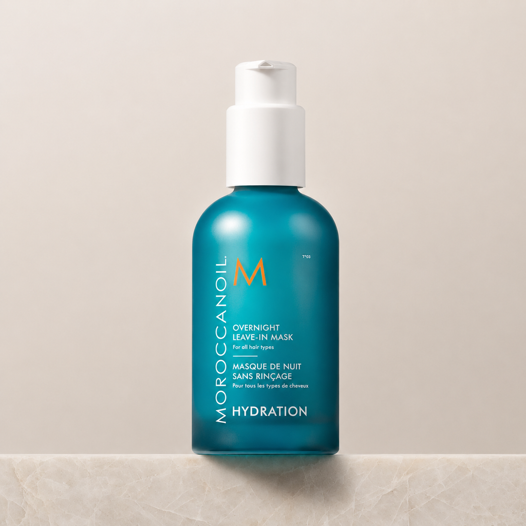 Masque de nuit sans rinçage Moroccanoil Hydration en flacon turquoise avec pompe blanche, présenté sur un comptoir clair.