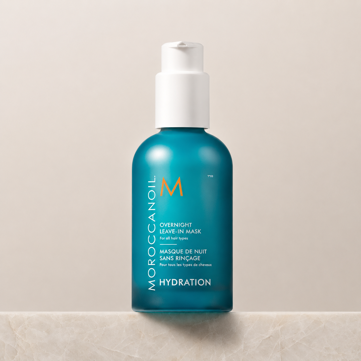Masque de nuit sans rinçage Moroccanoil Hydration en flacon turquoise avec pompe blanche, présenté sur un comptoir clair.