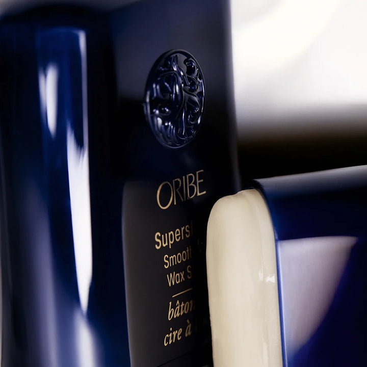 Gros plan du bâton de cire à lisser ORIBE Supershine bleu foncé avec texture de cire visible, produit coiffant brillant anti-frisottis.