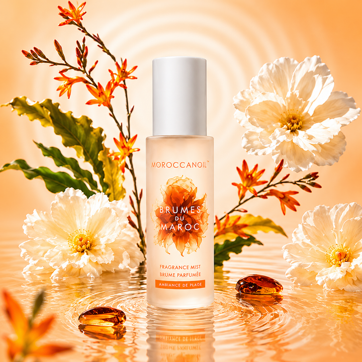 Brume parfumée Moroccanoil Ambiance de Plage 100 ml avec bouteille givrée beige orangé, fleurs blanches et reflets d’eau dorés sur fond lumineux tropical.