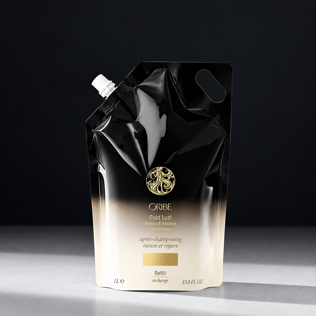 Recharge ORIBE Gold Lust Repair & Restore Conditioner 1 L, sachet souple noir et ivoire avec bouchon blanc, logo doré, photographié sur fond sombre.