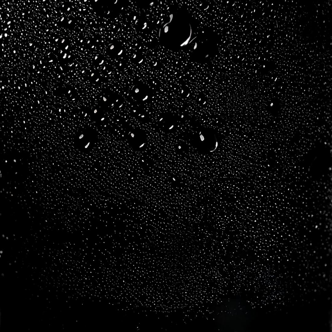 Brume fine de laque capillaire diffusée sur fond noir, texture légère du spray coiffant pour fixation souple sans effet collant.
