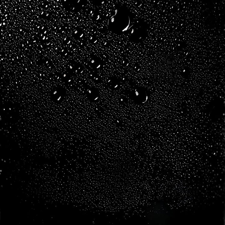 Brume fine de laque capillaire diffusée sur fond noir, texture légère du spray coiffant pour fixation souple sans effet collant.