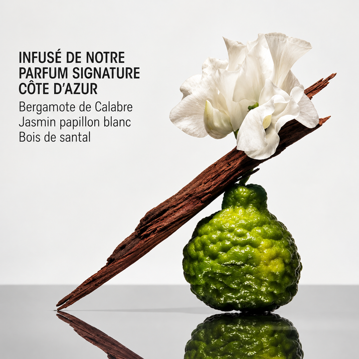 « Illustration du parfum Côte d’Azur d’ORIBE avec bergamote verte, fleurs blanches de jasmin et bois de santal sur fond gris clair réfléchissant. »